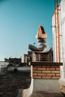 Rahat bir kadın terasta yoga egzersizi yapıyor..