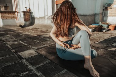 Relaxed woman practicing yoga on a rooftop terrace at sunset.