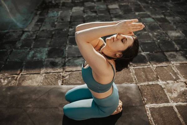 Rahat genç bir kadın terasta yoga yapıyor..