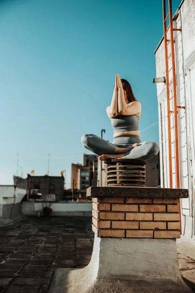 Rahat bir kadın terasta yoga egzersizi yapıyor..