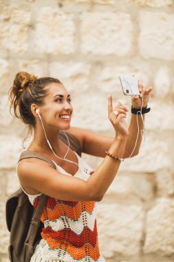 Akdeniz 'de yaz tatilinin tadını çıkarırken akıllı telefonuyla fotoğraf çeken gülümseyen genç bir kadın..