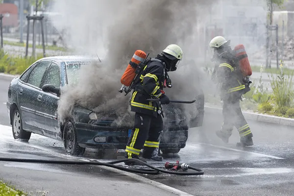 Firefighters are putting out a burning car Stock Picture
