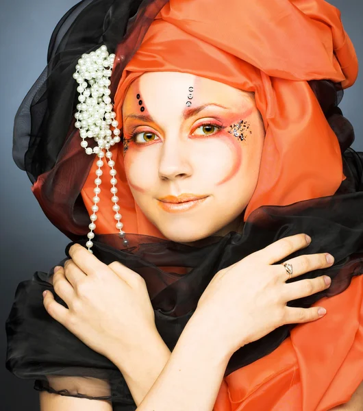 Mladá žena v černé a oranžové turban — Stock fotografie