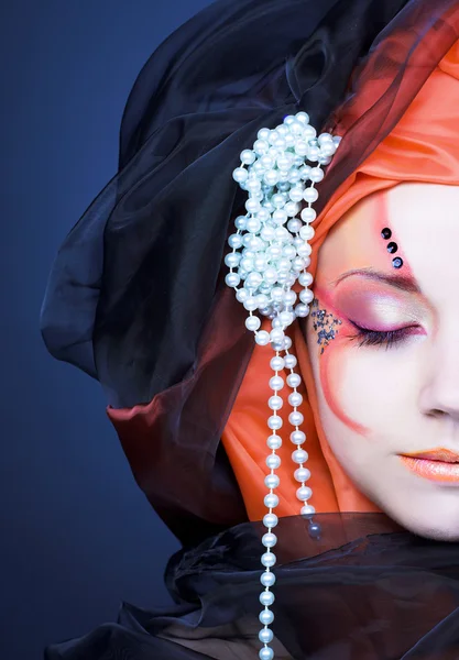 Mladá žena v černé a oranžové turban — Stock fotografie