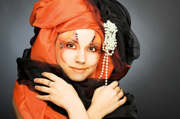 Mladá žena v černé a oranžové turban — Stock fotografie