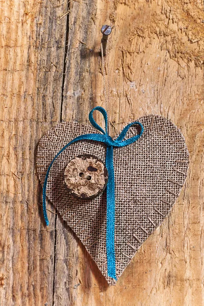 Украшение на деревянном фоне с тканевым сердцем — стоковое фото