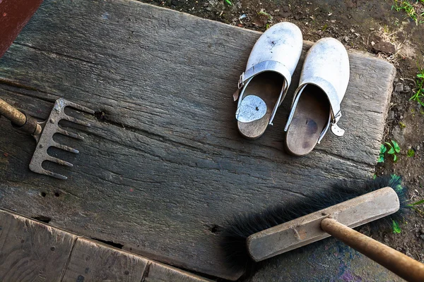 Clogs zapatos botas escoba cuerda rastrillo pórtico de madera escuelas — Foto de Stock