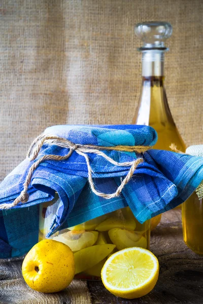 Tarro de alcohol membrillo licor en rodajas de frutas preparar entorno de madera — Foto de Stock