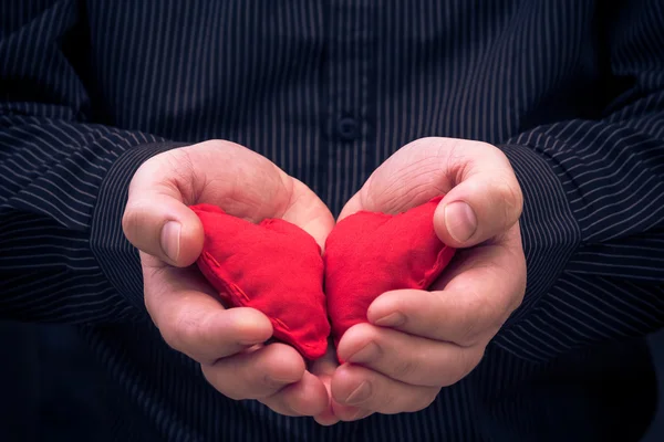 Dois corações vermelhos segurado mãos masculinas — Fotografia de Stock
