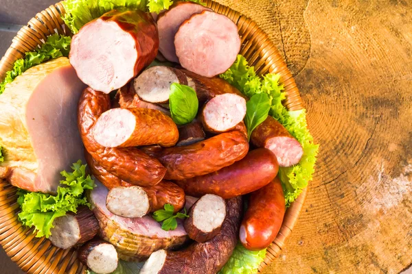 Verschillende vlees worst mand houten tafel achtergrond — Stockfoto