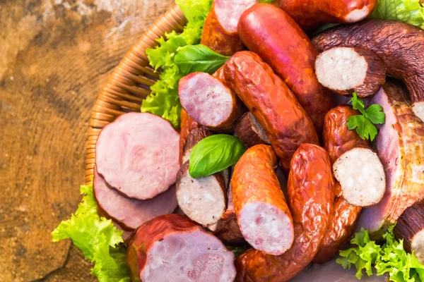 Verschillende vlees worst mand houten tafel achtergrond — Stockfoto