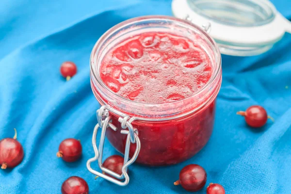 Kleine pot kruisbes jam blauwe stof — Stockfoto