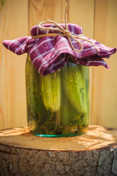 Jar pickled cucumbers wooden stump — Stock Photo, Image