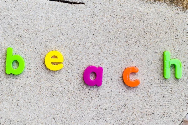 Het woord strand zand gelegd — Stockfoto