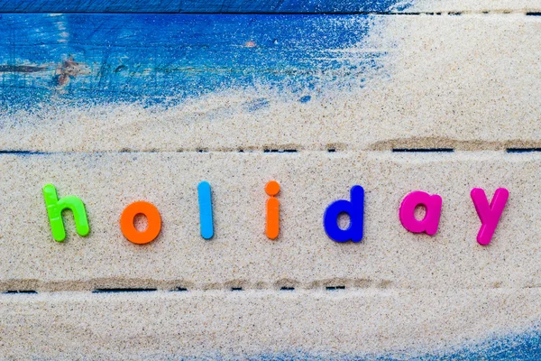 Palabra vacaciones puesta arena azul tablero —  Fotos de Stock
