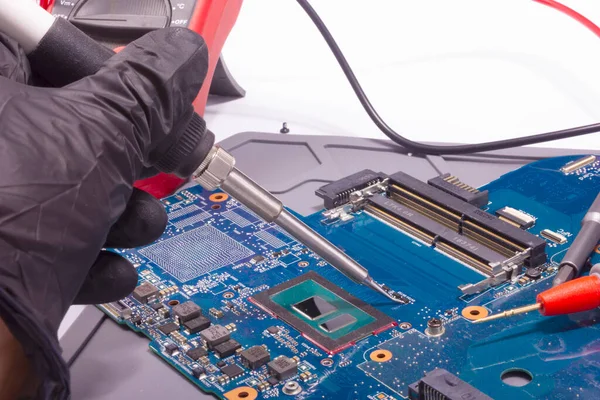 Laptop ana kartı tamir ediliyor. PCB üzerindeki elektronik bileşen lehimleniyor.