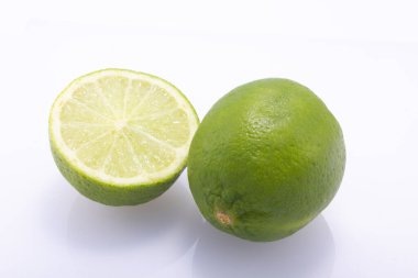 Yeşil limonlar, ikiye bölünmüş, beyaz bir torbaya karşı izole edilmiş.