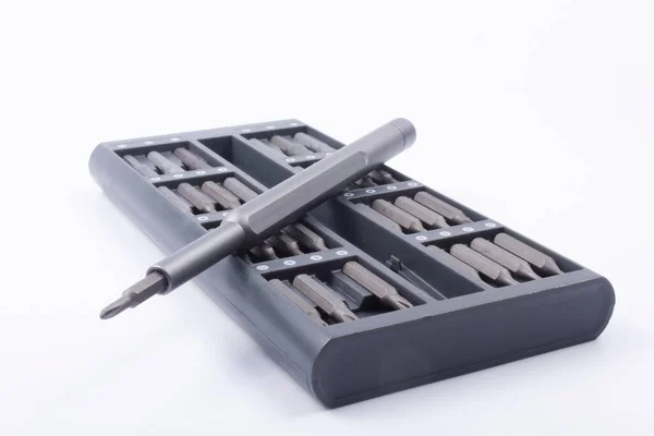 Hassas metal, gri tornavida ve beyaz arka plandaki özel bir kutuda bir takım değiştirilebilir bitler.