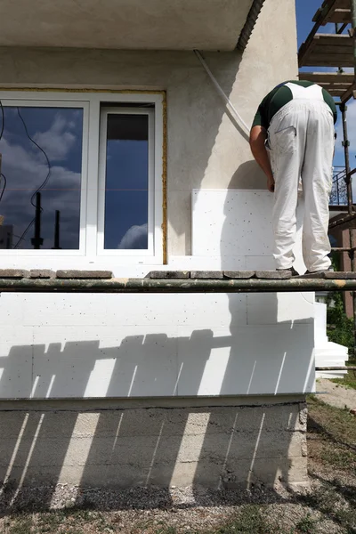 Werknemer styrofoam vel isolatie aan de muur te plaatsen — Stockfoto