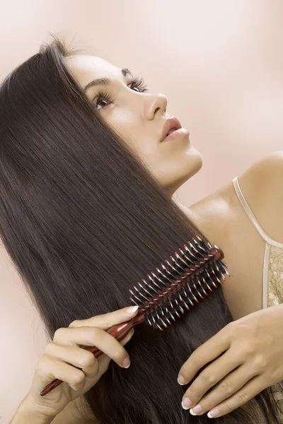 Retrato de una joven agradable ocupada con su cabello — Foto de Stock