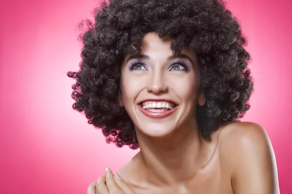 Close up portrait of young woman in afro wig on pink back Stock Photo