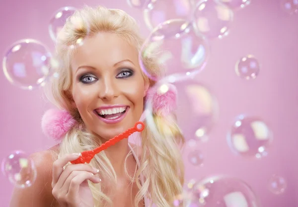 Retrato de jovem mulher agradável com bolhas de sabão nas costas rosa — Fotografia de Stock