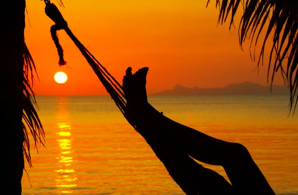 Vista de uma mulher descansando na rede durante o pôr do sol — Fotografia de Stock