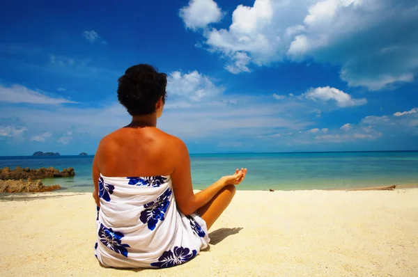 Vista de uma mulher meditando na praia no início da manhã — Fotografia de Stock