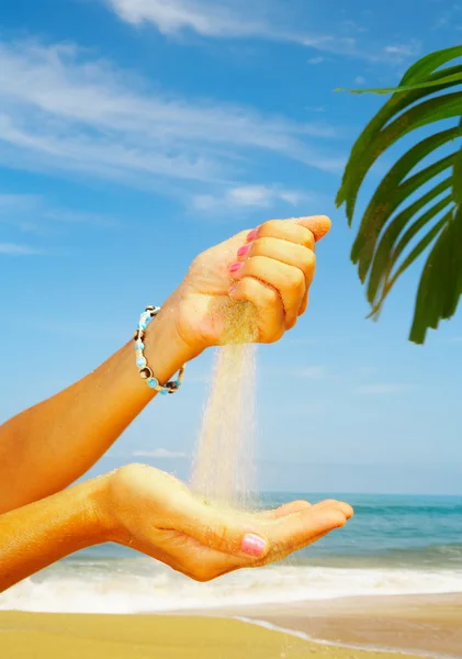 Weergave van dames hand spelen met zand op het strand — Stockfoto