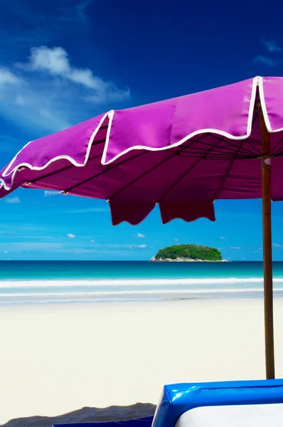 View of nice violet umbrella and small tropic island in the distance — Stock fotografie