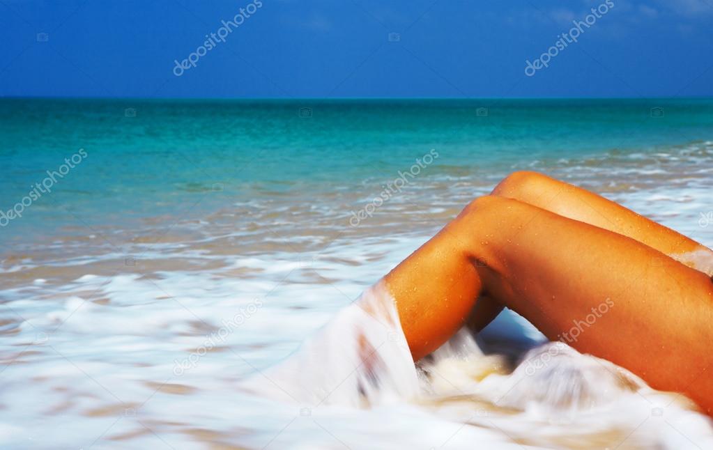 View of nice smooth womens legs getting splashed by tropical water