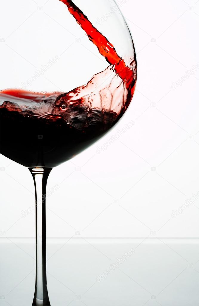 Close up view of wineglass getting filled with red wine