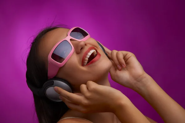 Glamour retrato de joven morena en gafas de sol rosadas escuchando música —  Fotos de Stock