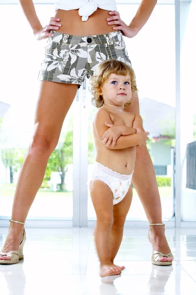 Retrato chave alta de bebê agradável andando entre as pernas das mães — Fotografia de Stock