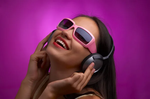 Glamour retrato de joven morena en gafas de sol rosadas escuchando música —  Fotos de Stock