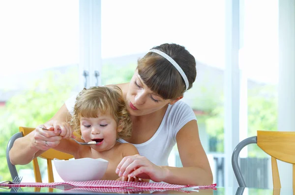 Portrait of young woman feeding her baby daughter — Stock Photo, Image