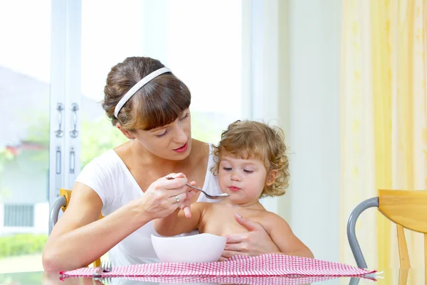 Portrait of young woman feeding her baby daughter — Stock Photo, Image