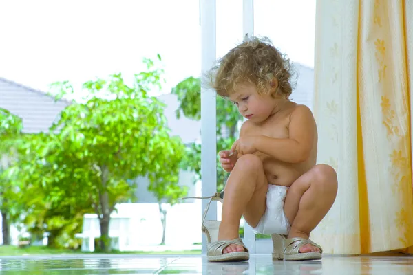 Hoge belangrijke portret van baby probeert te zetten op mamas schoenen — Stockfoto