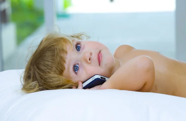 Wysokiej kluczowych portret młodego dziecka z telefonu komórkowegouśmiechający się oceniających za pomocą zestawu słuchawkowego — Zdjęcie stockowe