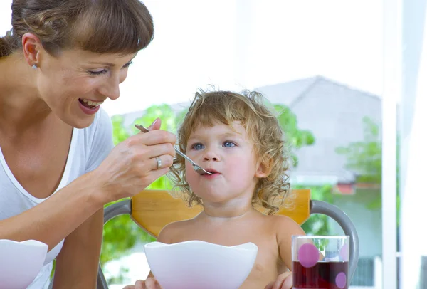 Porträt einer jungen Frau, die ihre kleine Tochter füttert — Stockfoto