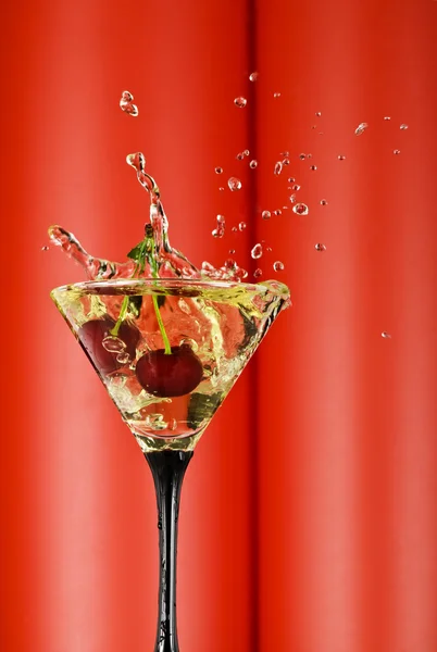 View of martini glass with vermouth and cherry dropping in — Stock Photo, Image