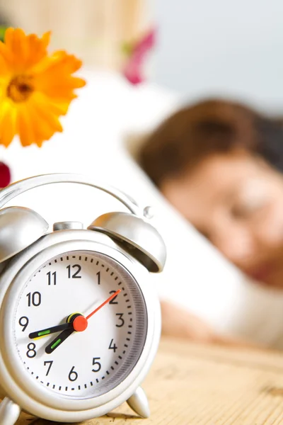 Vista de cerca del reloj de mesa y la mujer durmiendo en la espalda — Foto de Stock