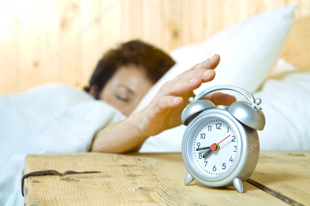 Close up view of table clock and woman sleeping on back