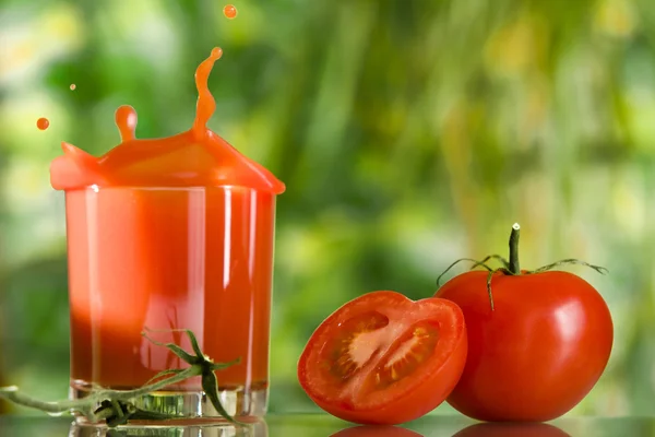 Vista de buenos tomates rojos y un vaso de jugo al lado — Foto de Stock