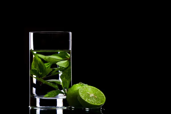 View of glass filled with green tea and some limes aside — Stock Photo, Image