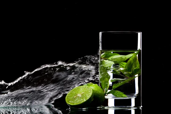 View of glass filled with green tea and some limes aside — Stock Photo, Image