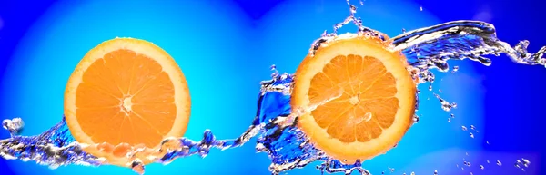 Nahaufnahme von zwei geschnittenen Orangenstücken, die mit Wasser bespritzt werden — Stockfoto