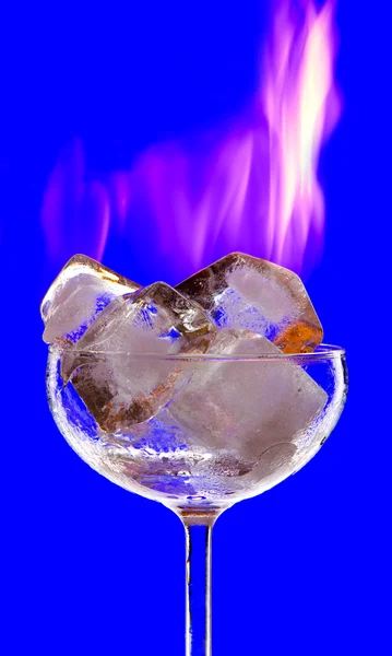 View of cocktail glass filled with burned ice on blue back Stock Image
