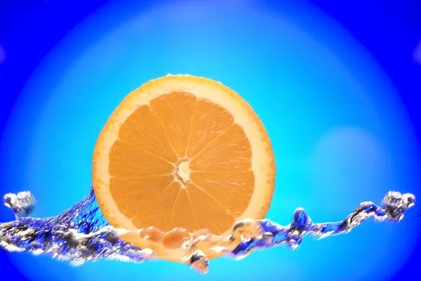 Vista de cerca de la pieza de naranja en rodajas que se salpica con agua — Foto de Stock