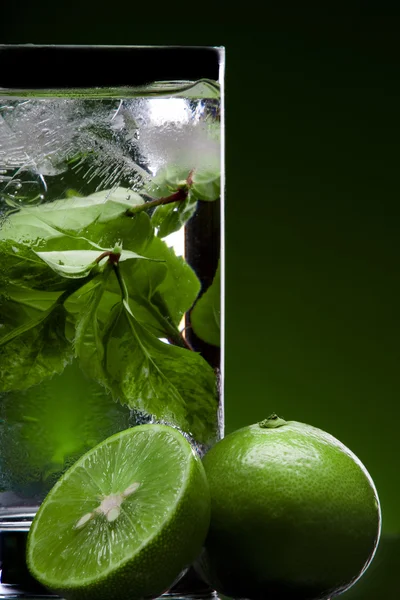 Vista de vidrio lleno de té verde y algunas limas cercanas — Foto de Stock